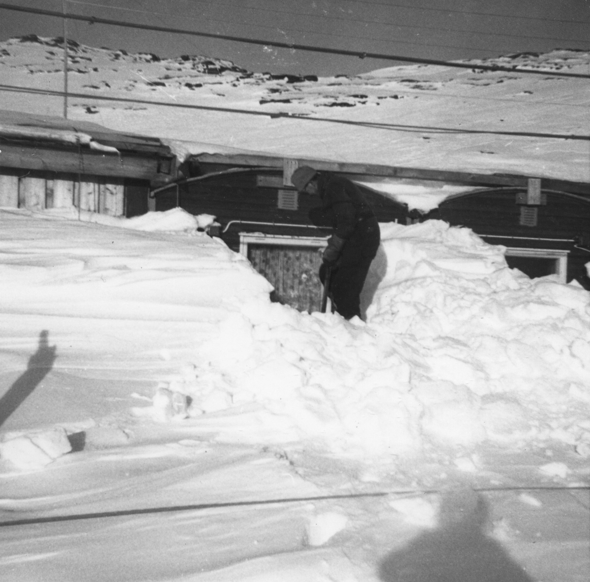 Anleggsarbeidar måker snø ved brakka i Vinkelen.