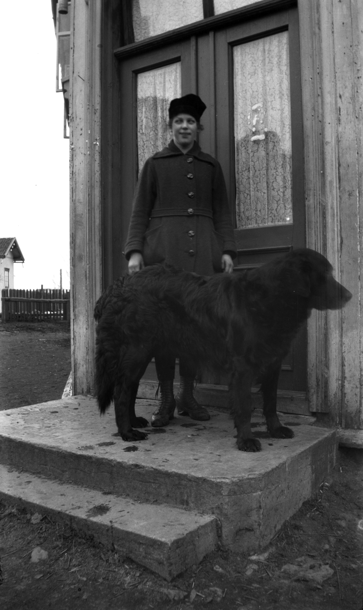 Ukjent jente ved et inngangsparti med en hund. 