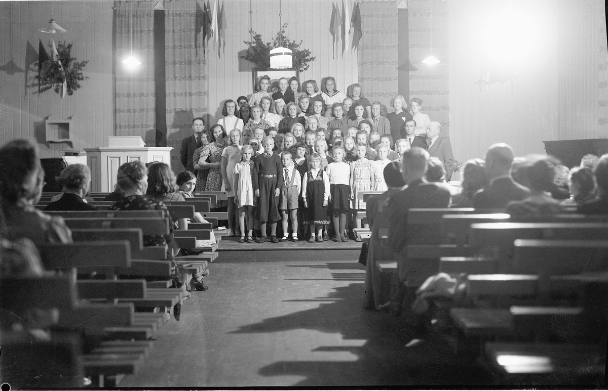 Ringsaker, Moelv, Søndagsskolestevne fra 1944-45 på Moelven bedehus (nå Kjærstad elektriske). Noen av de voksne: Ole Hagen til venstre i barnesangkoret, John Strømman og pastor Kr. Syvertsen til høyre, søndagsskole,