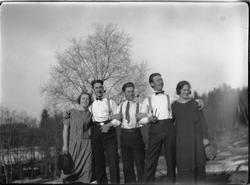 To kvinner og tre menn. Mennene røyker pipe.