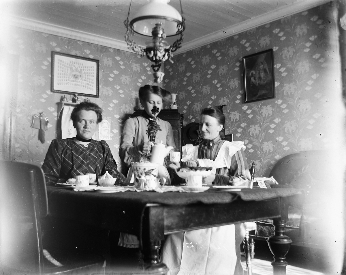 Interiør, stue. Kaffeservise. Fra høyre: Fru bakermester Lovise Larsdatter Johannessen(gift med Olaus Johannessen), hennes datter Louise Johannessen, Lydia Paulsdtr. Maurud(datter av Paul Larsen Maurud på Helgøya som er Lovise sin bror)