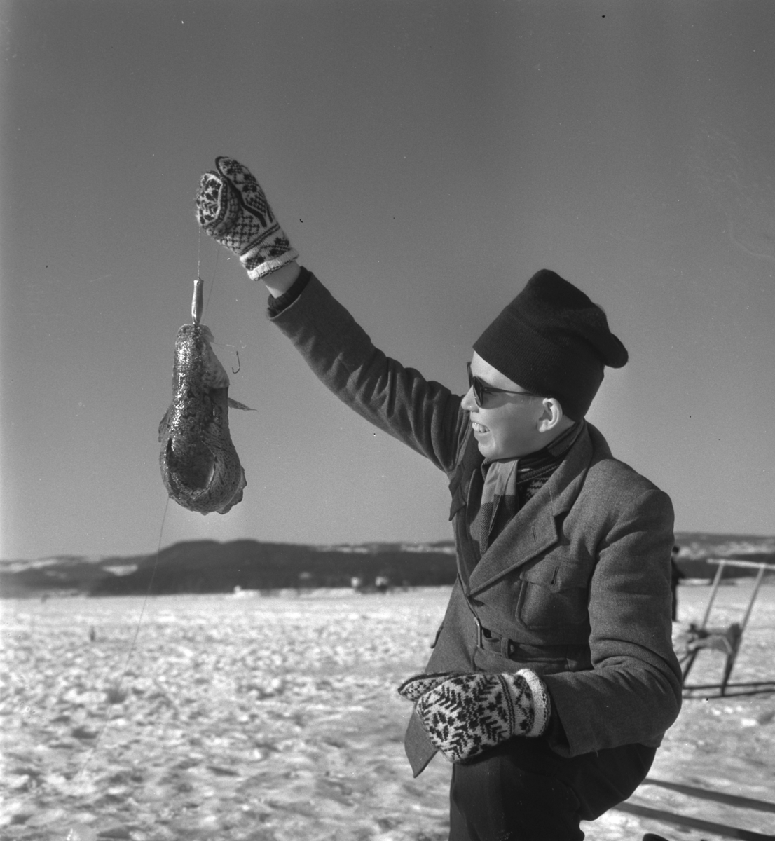 Pilkekonkurranse utenfor Strandsaga i Brumunddal 09. 03. 1958. Fiskekonkurranse på Mjøsisen. Isfiske. ukjent pilker. 
Premier i pilkekonkurransen var bla. en bil, Skoda 1958 modell, motorsykkel, kjøleskap, reiseradio. Se. Na-00293-31 og Na-00293-32 for flere opplysninger. 