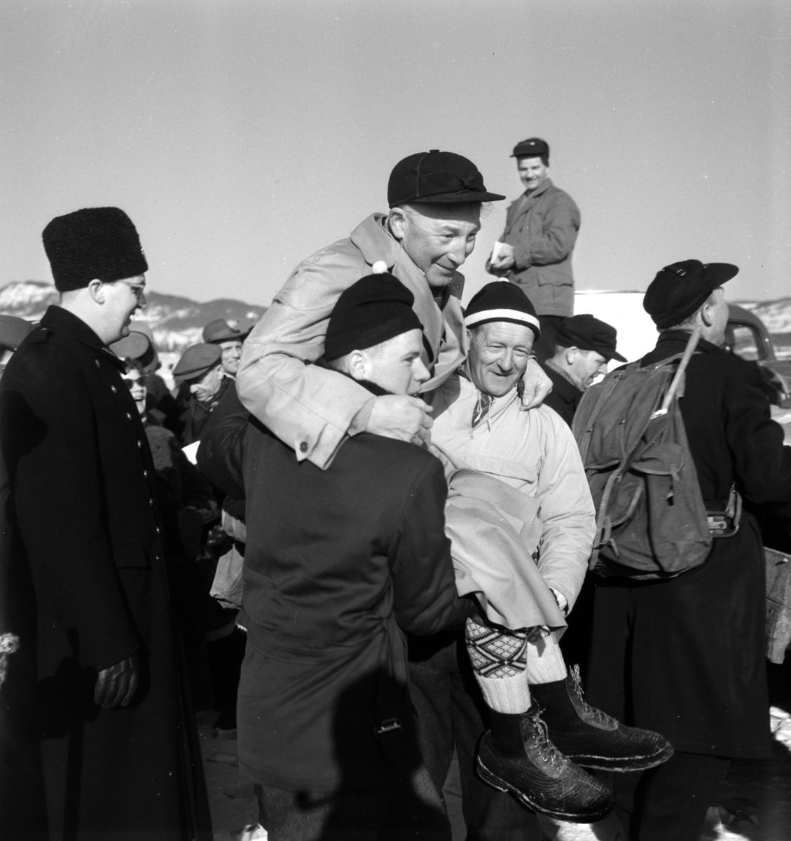 Pilkekonkurranse utenfor Strandsaga i Brumunddal 09. 03. 1958. 
Vinneren av pilkekonkurransen Nils Bjørnerud fra Furnes bæres på gullstol.  Fiskekonkurranse på Mjøsisen. Isfiske. 
Premier i pilkekonkurransen var bla. en bil, Skoda 1958 modell, motorsykkel, kjøleskap, reiseradio. Se. Na-00293-31 og Na-00293-32 for flere opplysninger. 