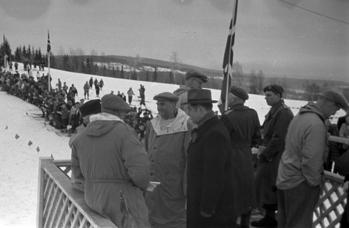 NM. Norgesmesterskap på ski, langrenn på Høsbjør i Furnes 1949. Skisport. Vinteridrett. Ærestribunen. kronprins Olav i samtale med blant annet rådmann i Hamar Sigurd Pedersen. 