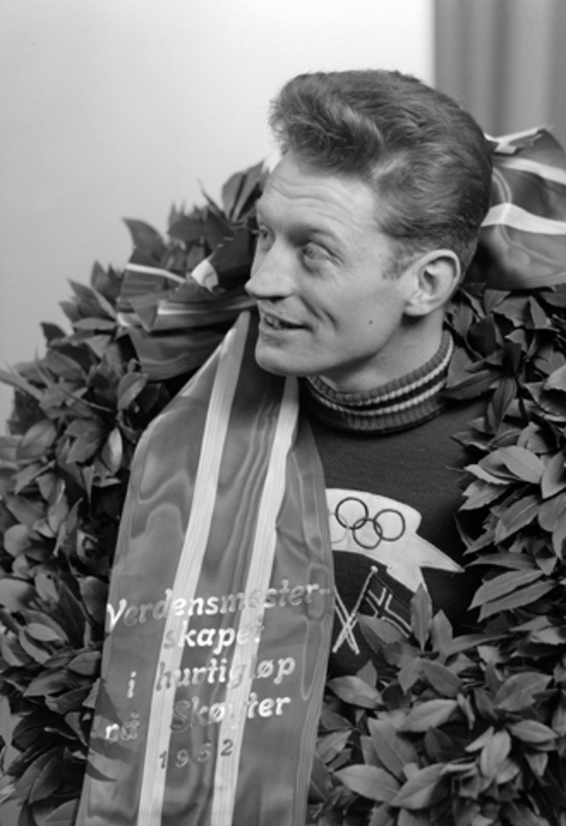 Hamar, skøyteløper Hjalmar Hjallis Andersen verdensmester med laurbærkransen i fotograf Normanns studio, verdensmesterskap allround på skøyter 1952, VM 1952 på Hamar stadion, hans tredje verdensmesterskap, med olympia antrekket - trikot, (to uker før 10. februar 1952 satte han ny verdensrekord ved et skøytestevne på Hamar med 16,32,6)
