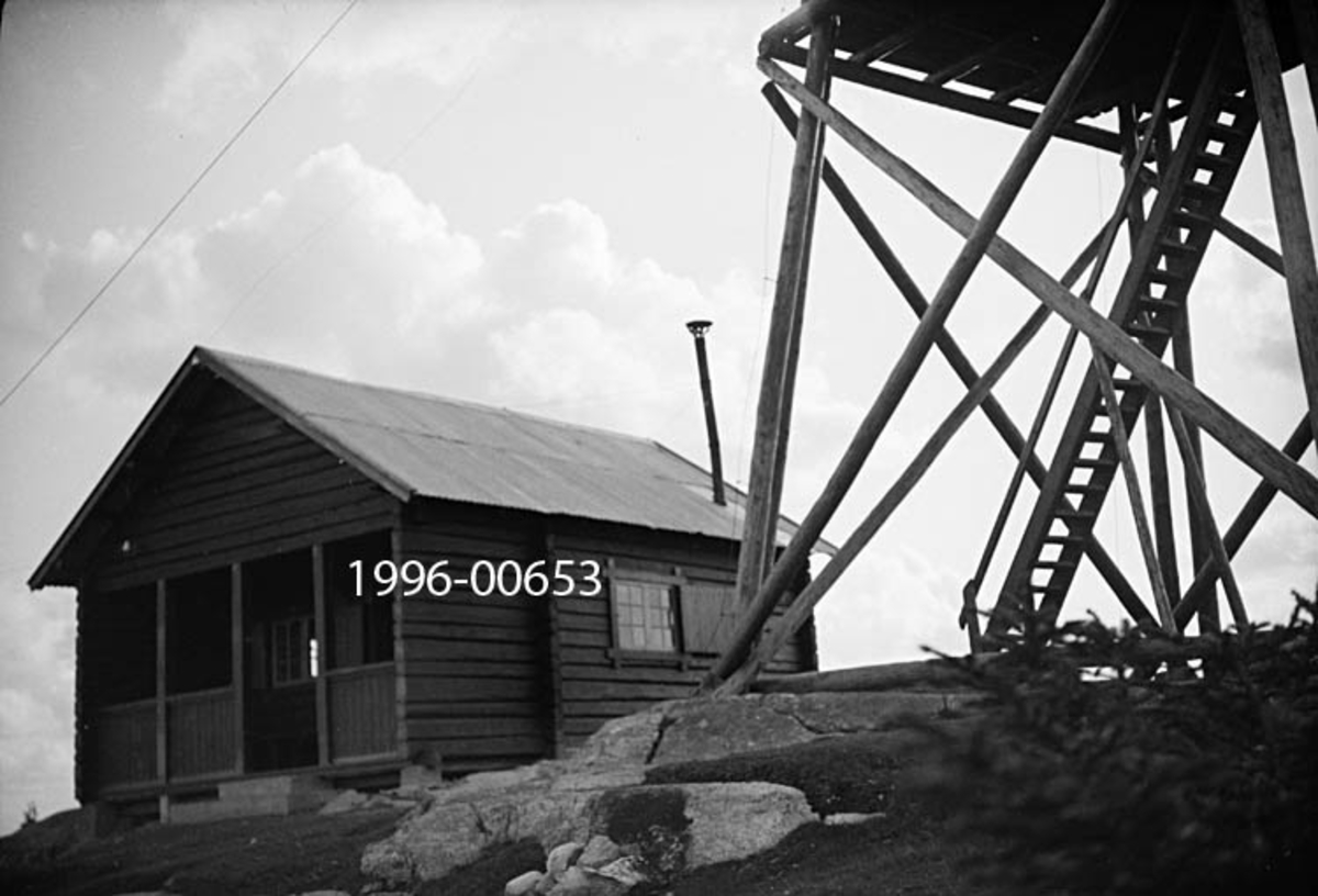 Blåenga skogbrannvakstasjon i Våler i Hedmark.  Stasjonen ligger 626 meter over havet.  Det første anlegget her ble reist av lokale skogeiere i 1907, men det tårnet som vises på fotografiet er antakelig det andre, som ble reist med støtte fra forsikringsselskapet Skogbrand i 1933.  Dette ble seinere (1951) erstattet av et ståltårn.  Hovedmotivet her er imidlertid hytta som tjente som bolig for brannvakten. 

Hytta er oppført i laftetømmer.  Den har rektangulært grunnplan og inneholder ett rom med åpen veranda foran inngangsdøra på gavlenden.  På langveggen er det et vindu med varelem.  Et blikkrør som stikker opp gjennom bølgeblikktaket var sannsynligvis røykavløp for komfyren inne i hytta. 

Etter at skogbrannvaktholdet på Blåenga ble avviklet huset og tårnet (det som ble bygd etter det vi ser på fotografiet) stående, og stedet ble et turmål for mange fra Våler og Åsnes.  I 2014 tok Rud velforening initiativ til restaurering av anlegget.  Fylkesmannen i Hedmark bidro med 100 000 kroner fra budsjettposten for «miljøtiltak i skog», vålersokningen Roar Johansen skjøt til 50 000 kroner og Våler skogeierlag skjøt til 30 000 kroner.  Våler Bygg AS påtok seg en del av de bygningsmessige restaureringsoppgavene, og sponset prosjektet med 10 000 kroner.  Målet var at tiltaket skulle komme bygda og distriktet til gode.  I 2014 ble det registrert cirka 1 000 besøkende i gjesteboka på Blåenga.