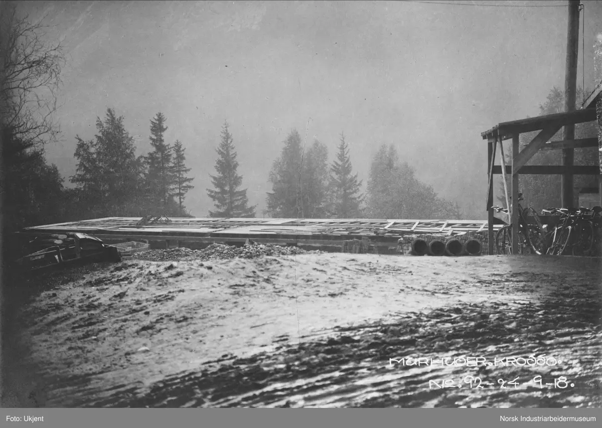 Murhusbebyggelsen på Krosso under oppføring. Grunnarbeider i gang på ett av husene. Skur med flere sykler stående ved vei.