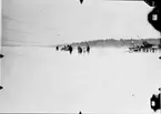 Kronprins Gustaf Adolf och prins Bertil besöker Hägernäs flygstation 1922. Personsällskap går mot en propellerdriven motorsläde ute på isen.