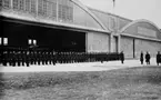 Manskap uppställt för inspektion framför en öppen hangar på F 2. Högre befäl framför.