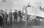 Flygplan M 2 med personer omkring på flygskolan på Malmslätt, 1913.

Carl Cederström i rutig tröja vänd mot kameran, därefter Emil Björnberg, Gösta von Porat samt Allan Jungner.