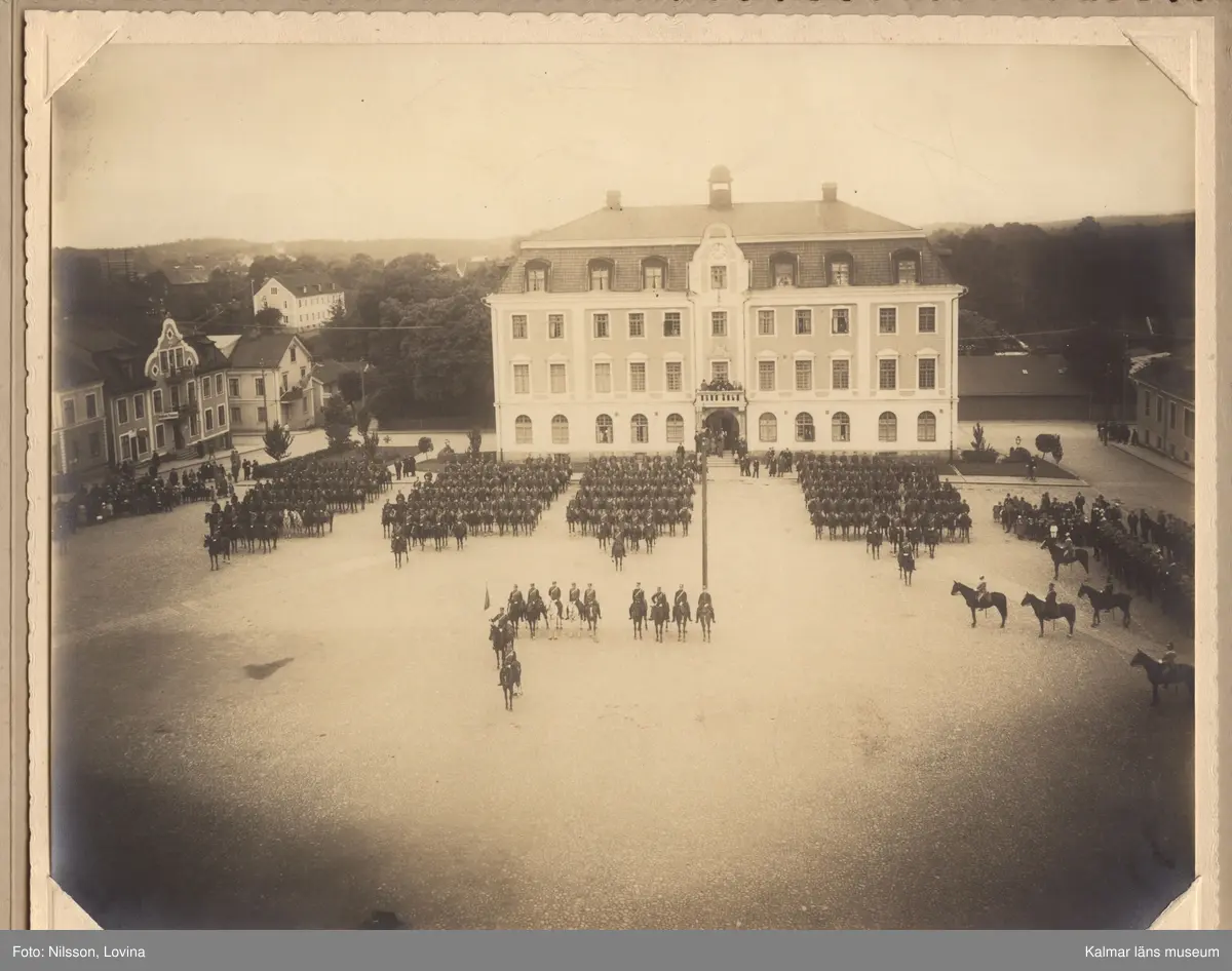 KLM 15433. Fotografi, i grått omslag av kartong. Mått: H 24,5 cm, Br 31 cm. Tre olika fotografier föreställande Kungliga Smålands Husarregementes paradering och gudstjänst på Eksjö torg 1923.