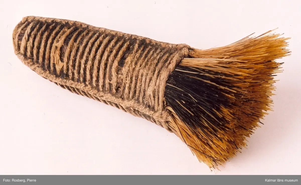 KLM 9855:1-2. Rakdon, består av borste och etui med spegel och luskam. :1 borste, längd 12 cm, diameter som mest 5 cm. :2 etui med spegel och kam, längd 11,5 cm, bredd 6,2 cm, tjocklek 1,8 cm. Borste av svinhår. Etuiets ena sida kan öppnas helt och har en spegel på insidan. Etuiets andra sidan har ett fack med skjutlock, i facket ligger en kam av ben. Dubbelkam, ena sidan kan användas som luskam.