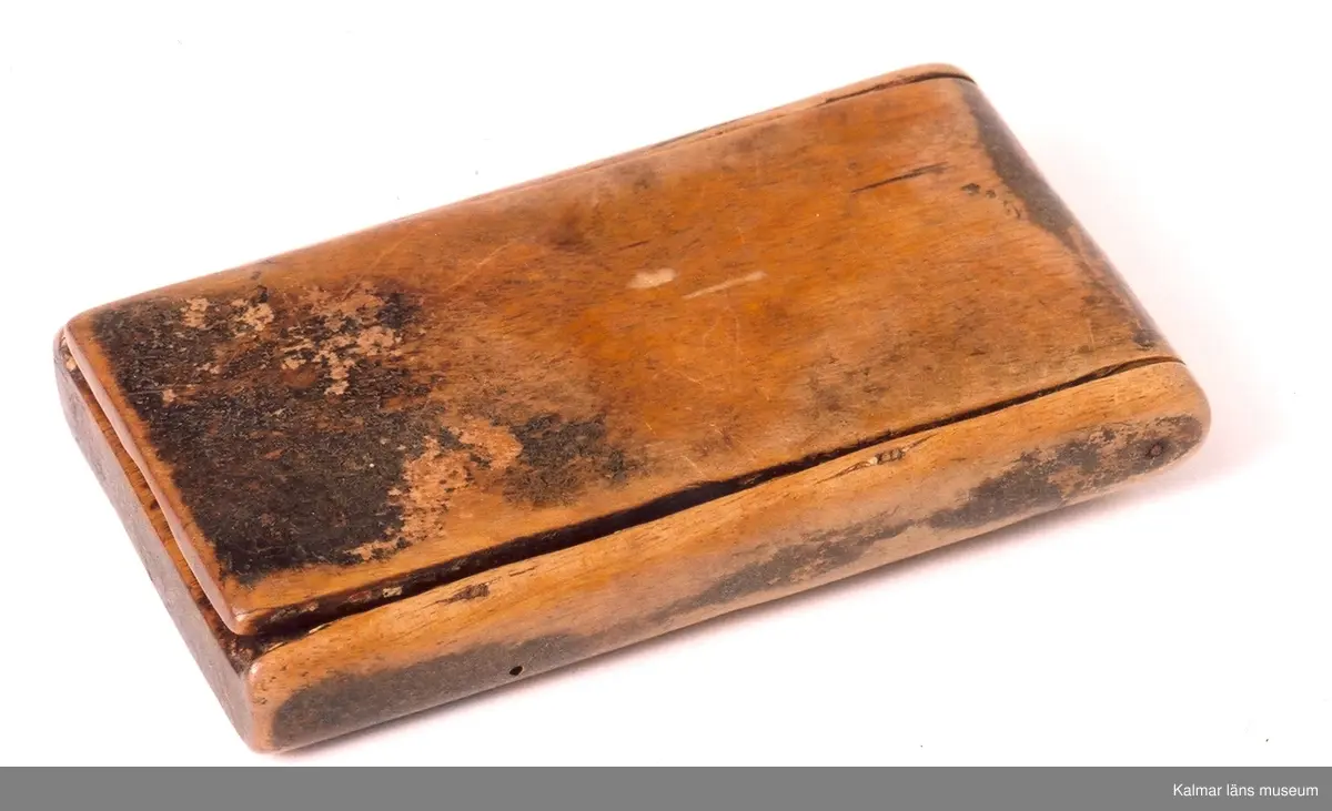 KLM 9855:1-2. Rakdon, består av borste och etui med spegel och luskam. :1 borste, längd 12 cm, diameter som mest 5 cm. :2 etui med spegel och kam, längd 11,5 cm, bredd 6,2 cm, tjocklek 1,8 cm. Borste av svinhår. Etuiets ena sida kan öppnas helt och har en spegel på insidan. Etuiets andra sidan har ett fack med skjutlock, i facket ligger en kam av ben. Dubbelkam, ena sidan kan användas som luskam.