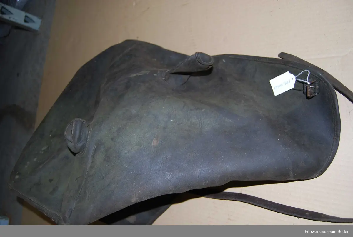 Kapell troligen för pjäs eller liknande. Av svart läder, med spännen. Rektangulär form med ena gaveln öppen. Två utstickande "horn".