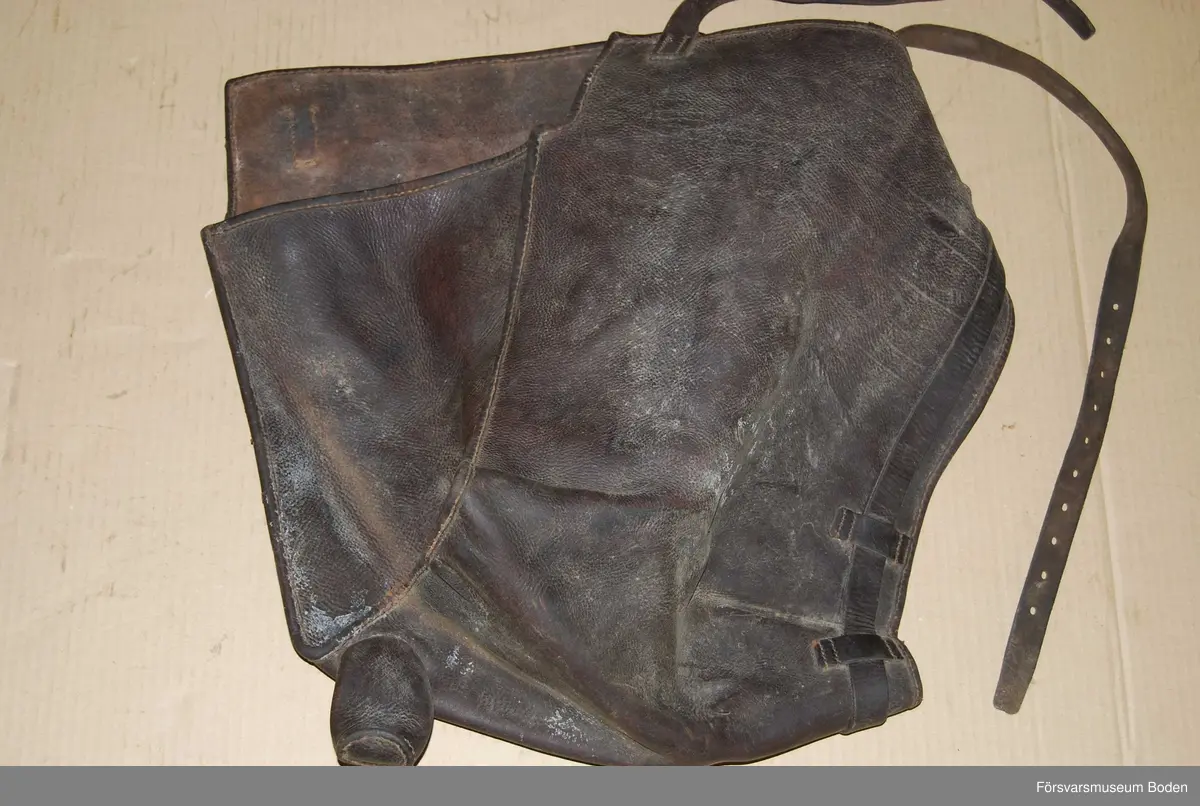 Mörkbrunt läder med ett utskjutande "horn". Ena gaveln öppen. Troligen till pjäs.