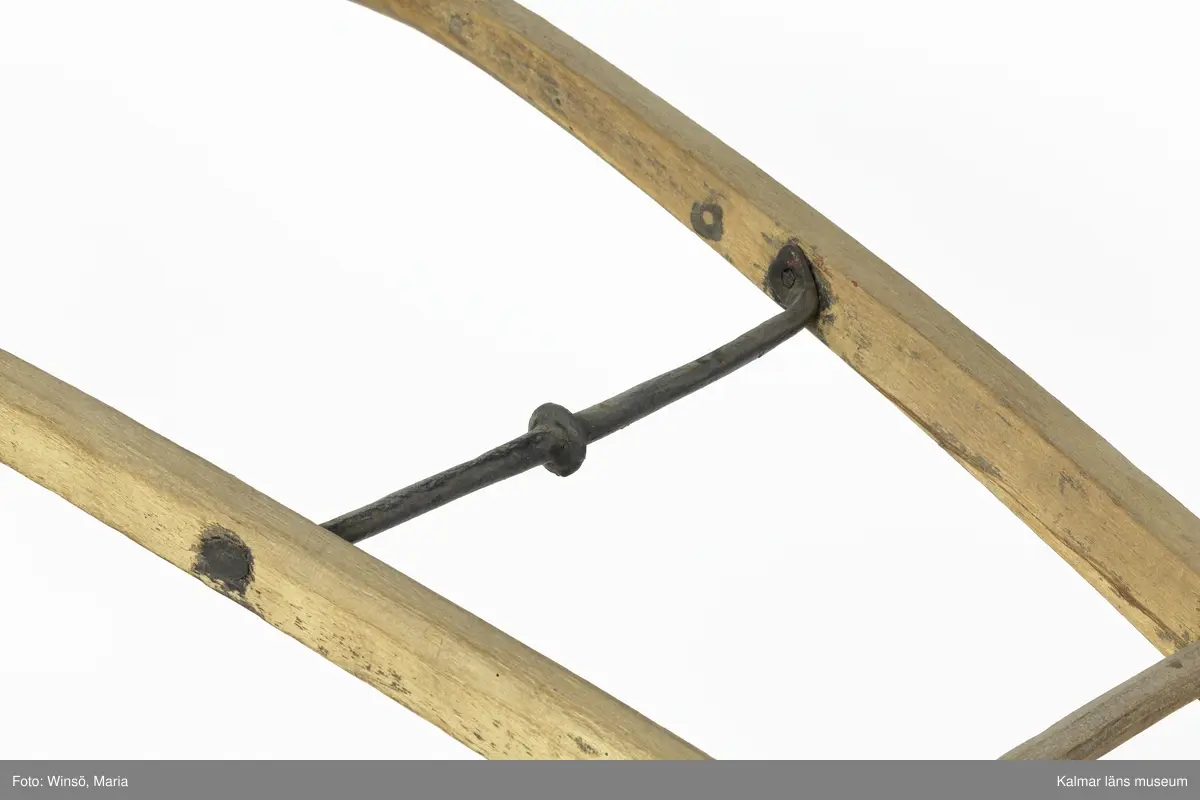 KLM 12823. Plog, trä, metall. Plog med handtag och ås av trä. På åsens ena sida sitter en rist av järn fastskruvad. Längst ut på åsen en dragkrok av järn för anspänning av dragdjur. Plogblad med bill av järn. Träkil mellan plogblad och landsida. Plogen är järnskodd på undersidan. Den har även varit järnskodd på landsidan men denna saknas. Spikarna sitter kvar i träet. Fyra slåar mellan handtagen, två av järn och två av trä. Det nedersta är fastskruvat i plogbladet. Plogen är svartmålad med en röd eventuell rostskyddsfärg under. Målad under senare tid.