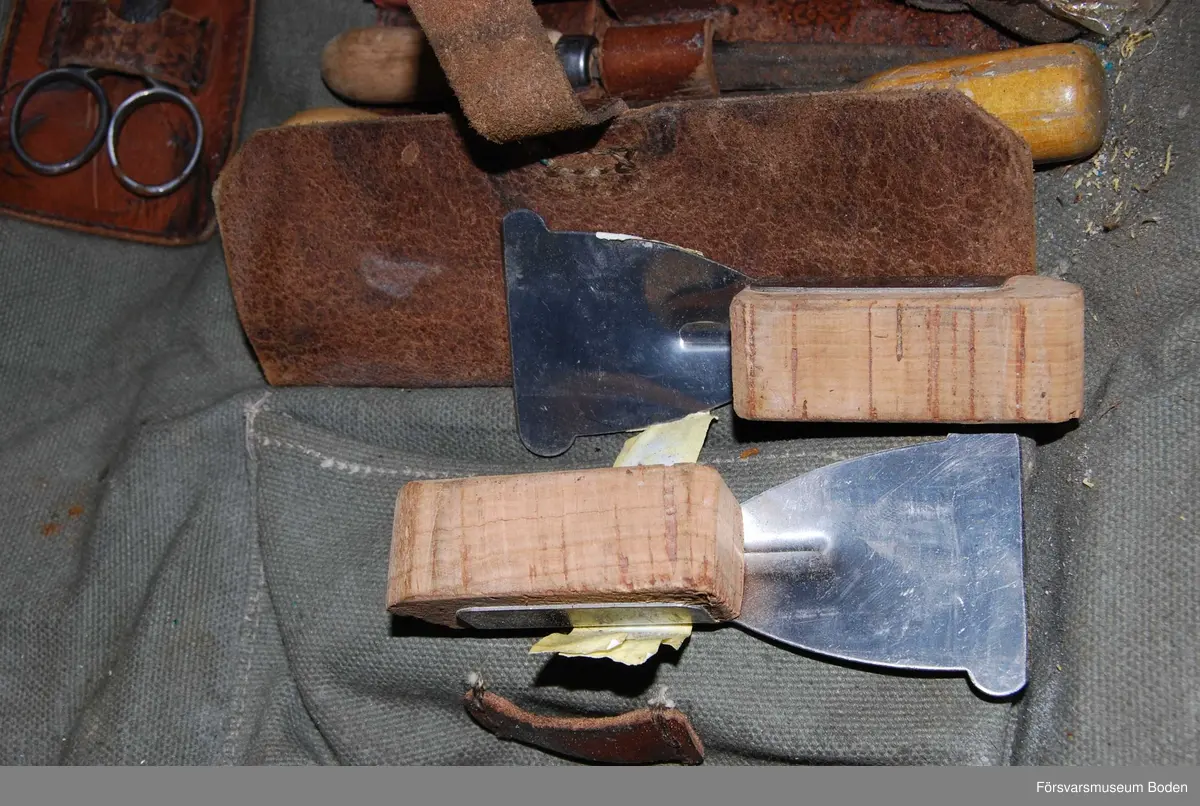 Verktygssats i väska av grågrönt textilmaterial med axelrem. Innehåller även förbrukningsmateriel som bleckplåtar, wire, nitar o.dyl. Väskan vikes upp och har hållare för verktyg i centrum samt tre fickor med lock. Materielnummer M8740-101110 enligt bifogad satslista.