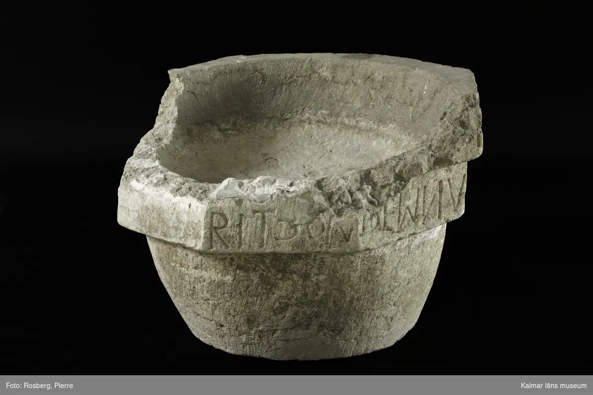 KLM 35218:1:1-4. Dopfunt, av kalksten, består av 4 delar. :1:1. Dopfuntscuppa, mått: mynning yttre diameter 65 cm, inner diameter 50 cm, skåldjup 18 cm, botten diameter 40 cm. Cuppan utförd i tre nivåer, de två övre delarna är åttakantiga och underdelen cylindrisk med svag konisk-konvex profil. Den övre åttakantiga nivån med latinsk inskription, text med versaler, inskrift: ...ERIT ET BABTATUS FUERIT SALV... Den undre åttakantiga nivån har texten ...RIT CONDEMNABITUR. (Inskriften är ej helt komplett, del av citat från, Marcus 16:16. Hela citatets översättning, Bibeln 2000: Den som tror och blir döpt skall räddas, men den som inte tror skall bli dömd.)  Den undre nivån har kryssristad dekor. Underdelen är odekorerad. Grund skål. Cuppans överkant, är till hälften bortslagen, tre av bitarna finns kvar. Utan uttömningshål. :1:2-4 tre lösa delar tillhörande övre kanten av cuppan. Alla tre delar har otydlig latinsk inskription, text med versaler och tecken.