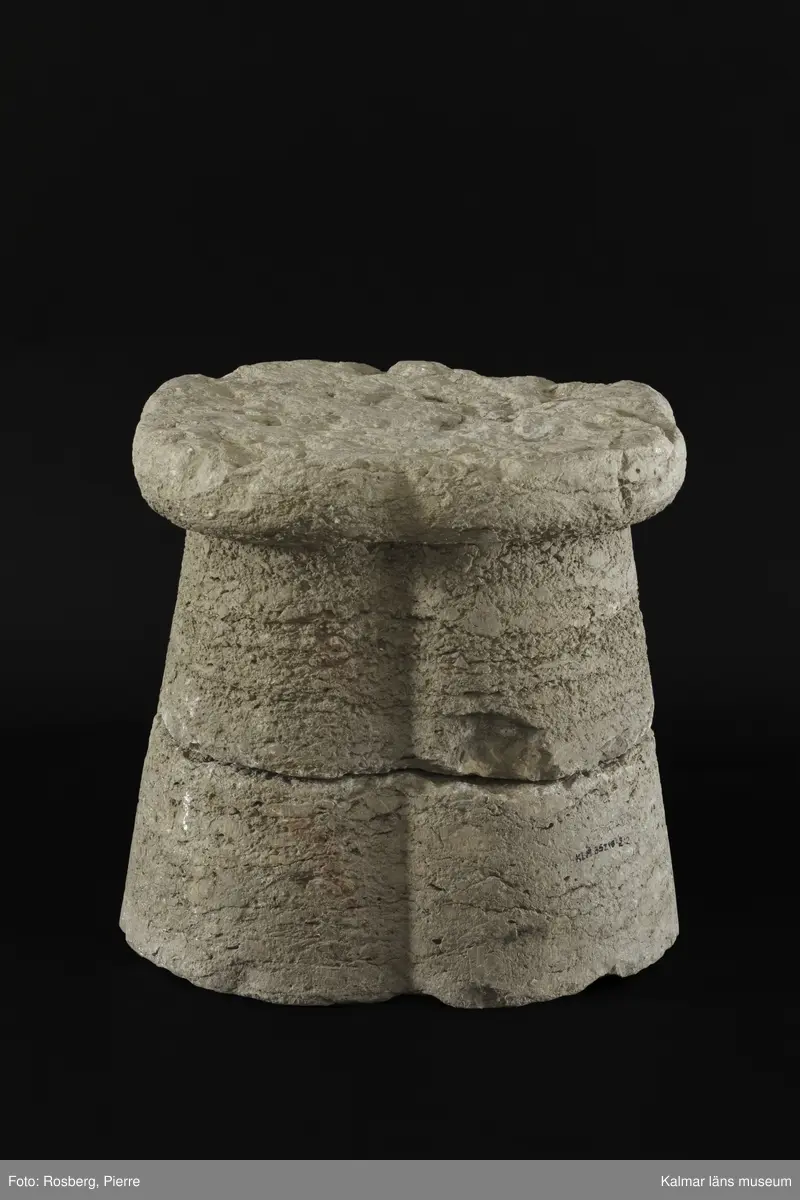 KLM 35218:2:1-2. Dopfuntsfot, av kalksten, 2 delar. Mått, hela foten: höjd 40 cm, största bredd 43 cm. Foten sammansatt av fyra halvkolonner, konade med fyrklöverformad vulst upptill. Saknar fotplatta. Foten som är det enda som återstår av funten är eroderad efter lång tid utomhus. Den har en liten skada vid skarven och en horisontell spricka.