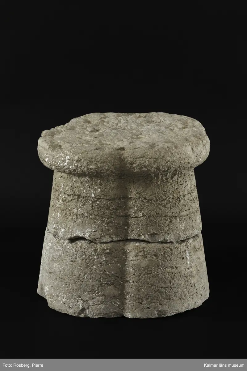 KLM 35218:2:1-2. Dopfuntsfot, av kalksten, 2 delar. Mått, hela foten: höjd 40 cm, största bredd 43 cm. Foten sammansatt av fyra halvkolonner, konade med fyrklöverformad vulst upptill. Saknar fotplatta. Foten som är det enda som återstår av funten är eroderad efter lång tid utomhus. Den har en liten skada vid skarven och en horisontell spricka.