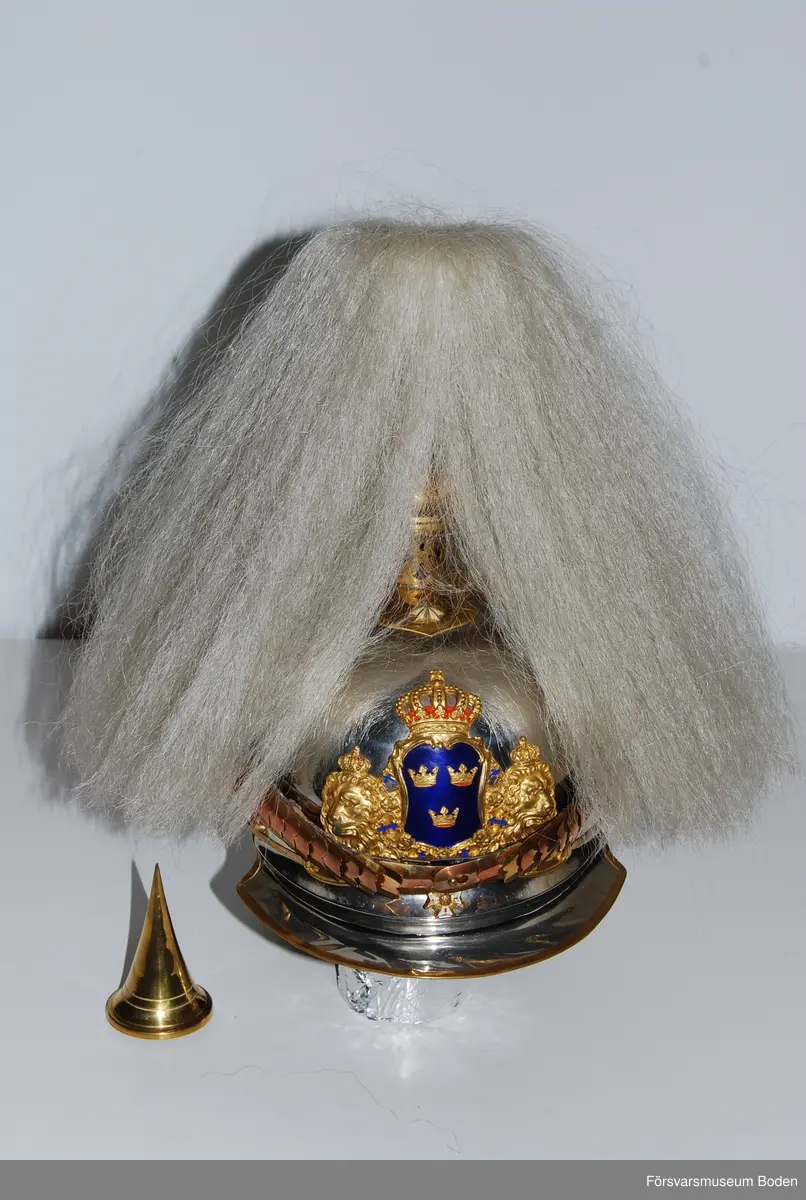 Förnicklad stålplåt med förgyllda beslag. Bl.a. förlängt nackstycke jämfört med tidigare m/1879. Upptill skruvfäste för plym m/1887 av vitt tagel (vid stor paraddräkt) eller pik, båda medföljer. Gul sidenkokard under hakremsknappen på höger sida. Framtill förgylld vapenplåt med blå emalj.