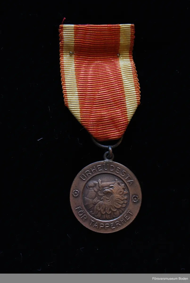 Tavla med uppsatta medaljer på svart sammet. Har tillhört Karl Hjalmar Lindskog, finlandsfrivillig 1939-1940. Från vänster på bilden:
1. Vinterkrigets minnesmedalj med svärd och spänne, Lappi, järn. Urkund finns i pärm under FMB.002361.
2. Frihetsmedaljen 2.klass, brons, urkund finns i pärm under FMB.002361.
3. Medalj från Föreningen för skolungdomens vapenövningar, silver.
4. Svärdstecken.
Överst på tavlan ett släpspänne för dessa medaljer.