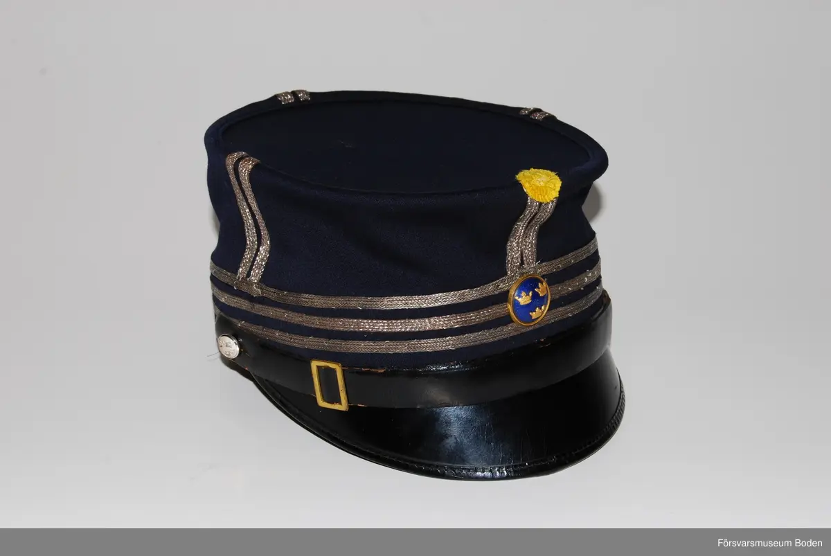 Av mörkblått kläde med tre smala silvergaloner runt mössan betecknande kapten. Framtill gul kokard samt mössknapp i blå emalj för officerare. Mössremmen fastsatt med regementets knapp modell mindre.