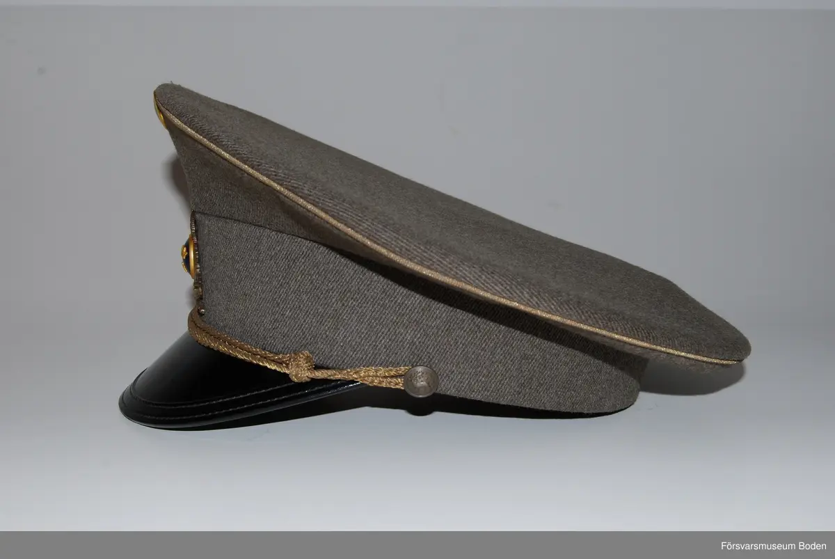 Gråbrungrönt ylletyg med mössmärke m/1939 i brons och blå emalj. Överst nationalitetesmärke m/1941. Mössrem bestående av flätad bred träns i bronsfärg för regementsofficerare, fäst på sidorna med regementets knapp modell mindre.