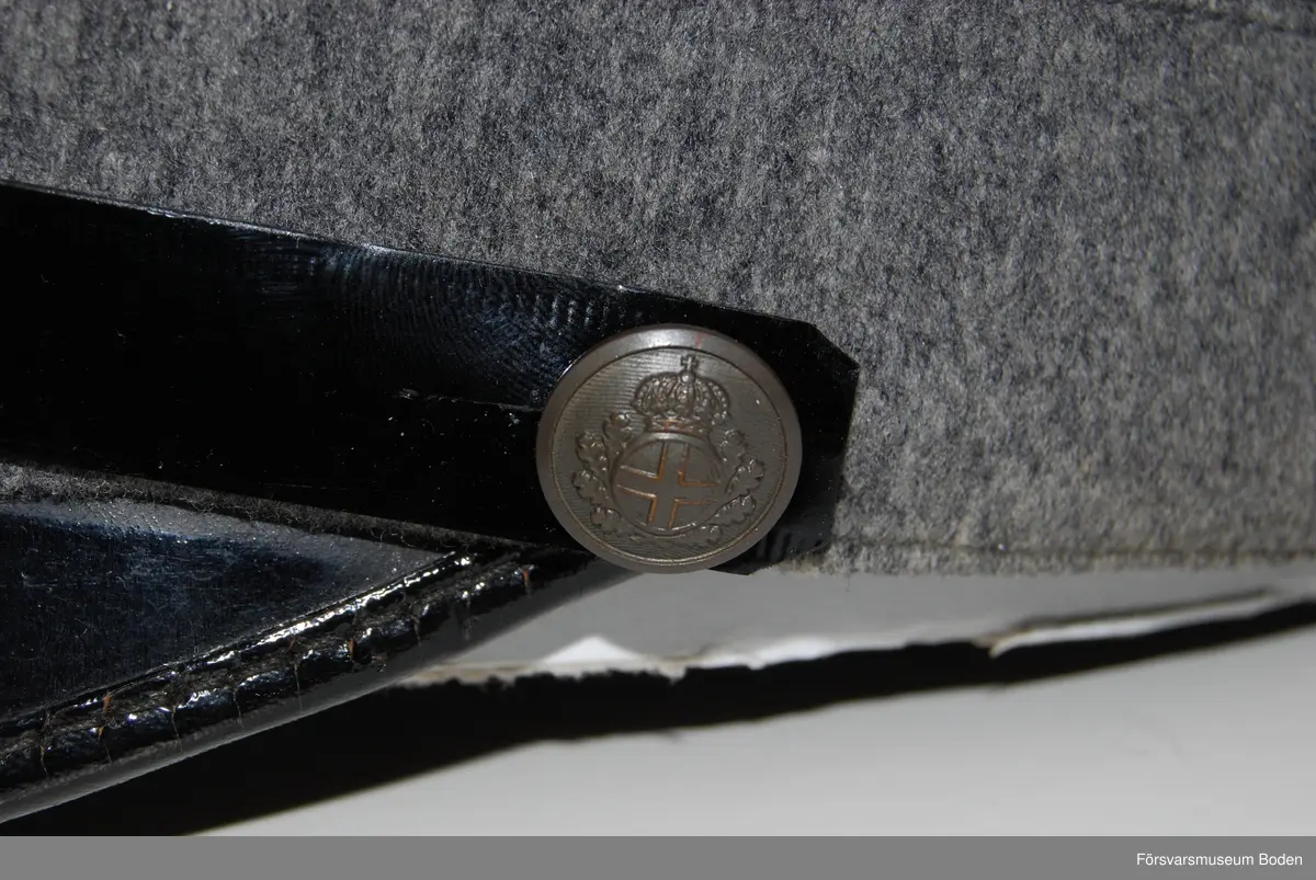 Ljusgrått kläde med tre smala band av blått kläde runt mössan betecknande kapten. Framtill mössmärke m/1865 i blå emalj samt upptill landstormsmärke m/1926 med gult broderat kors på blått kläde. Mössremmen fäst på sidorna med landstormens knapp modell mindre. Buren av fil. dr Arvid Moberg.