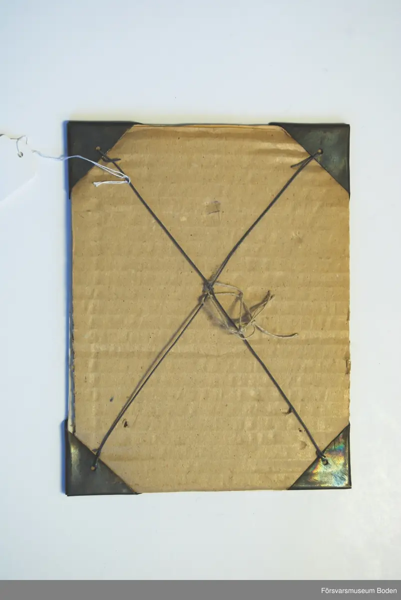Plansch 23 x 17 cm med glas och upphängningsanordning med kopparskodda hörn. Samma uniform som på plansch FMB.002686, men sedd från sidan.