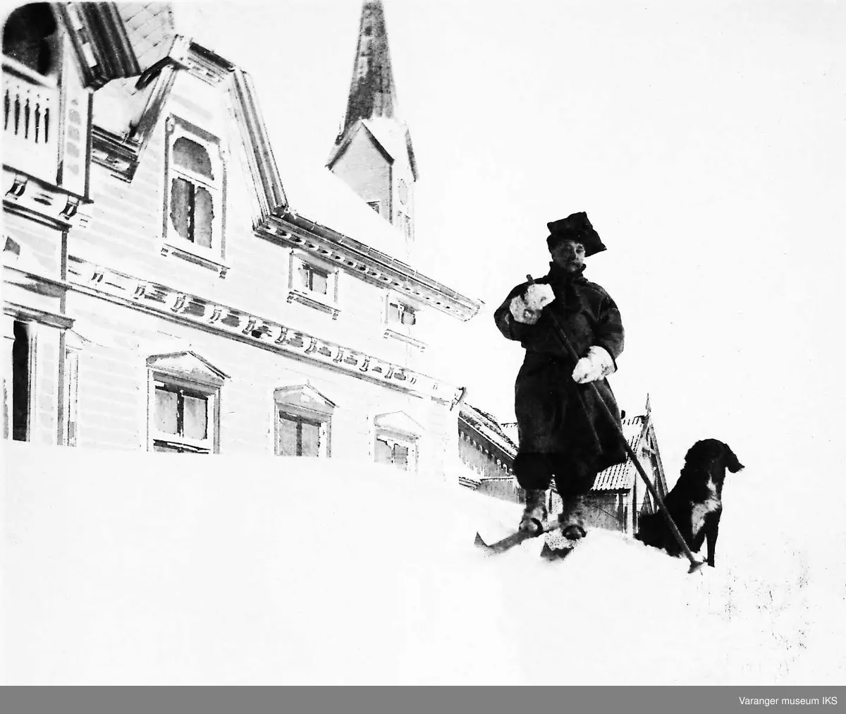 Postkort, postmann på ski med hund venter utenfor Amtmannsgården i Vadsø 1905.