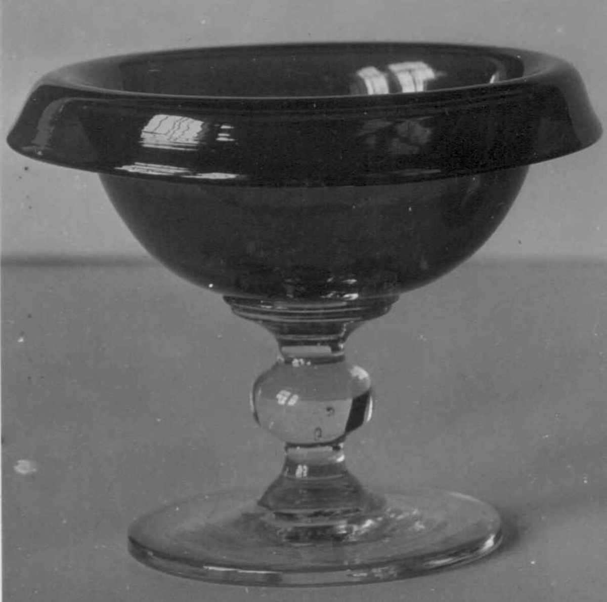 Glass. Blått, fot og stilk ufarget. Se NF.1901-0240 Av ark. Berntsen 1914 henf. til Gjøvik eller Biridalens glassverk, men ifølge samme 15.03.37 ant. ikke norsk.