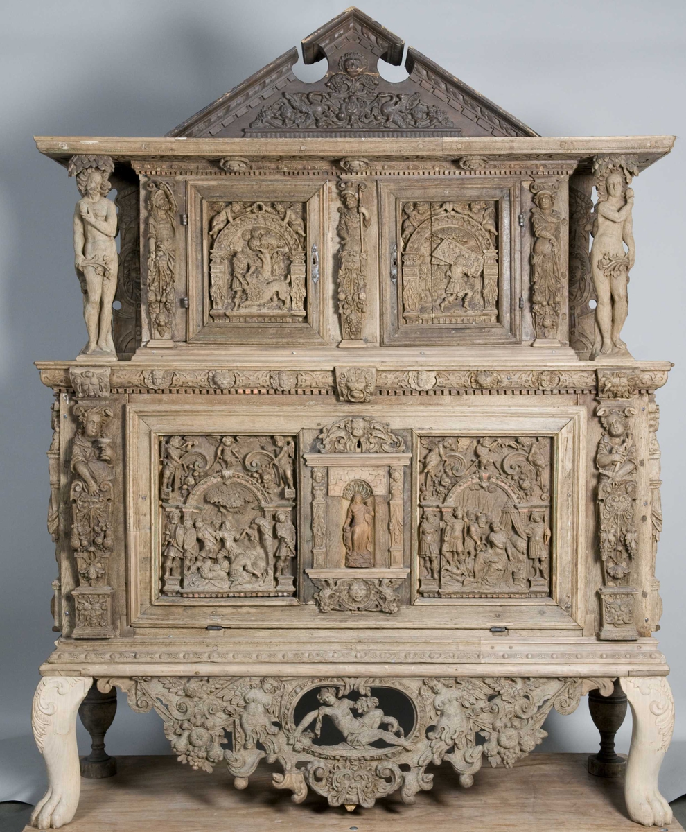 Rektangulært skap med skåret ornamentikk i flere deler. Øvre skap med to dører og gesims. Nedre skap med en klaff fremstilt som to dører. Skapdelene står på en sokkel med fire ben. Tympanon på øvre skap. Skapet ble opprinnelig brukt som skjenk med åpen klaff for å servere drikkevarer til gjester.
På overskapet i dørfyllinger er utskåret motiv fra gamle testament: "Samsons kamp med løven" og "Samson bærer bort Gazas byport". På underskap i fyllinger: "Samson slår filisterne med asenkjeven" og "Samson og Dalila". Dørene blir flankert av hermenpilaster. Mellom fyllinger på overskap aedikula med dyden "kjærlighet".  Som karyatide og atlant to utskårete figuerer "Adam og Eva" ved overskap. 
Klassiske profiler med eggstav, perlestav og tannsnitt. Beslagverkornament på skapsidene, gesimsens underside og profil på underskap. 
Utskårete hoder av løver, engler, kvinner, masker på gesimsens underside og profil på underskap. Sidebrett med hermer, portretter i medaljonger og beslagverk. Sokkelen består av dreide og utskårete ben, holdt av en ramme, Forsidens blending er dekorert med utskårete figurer og ornamenter i ørebruskstil.
Flere deler er sekundære.