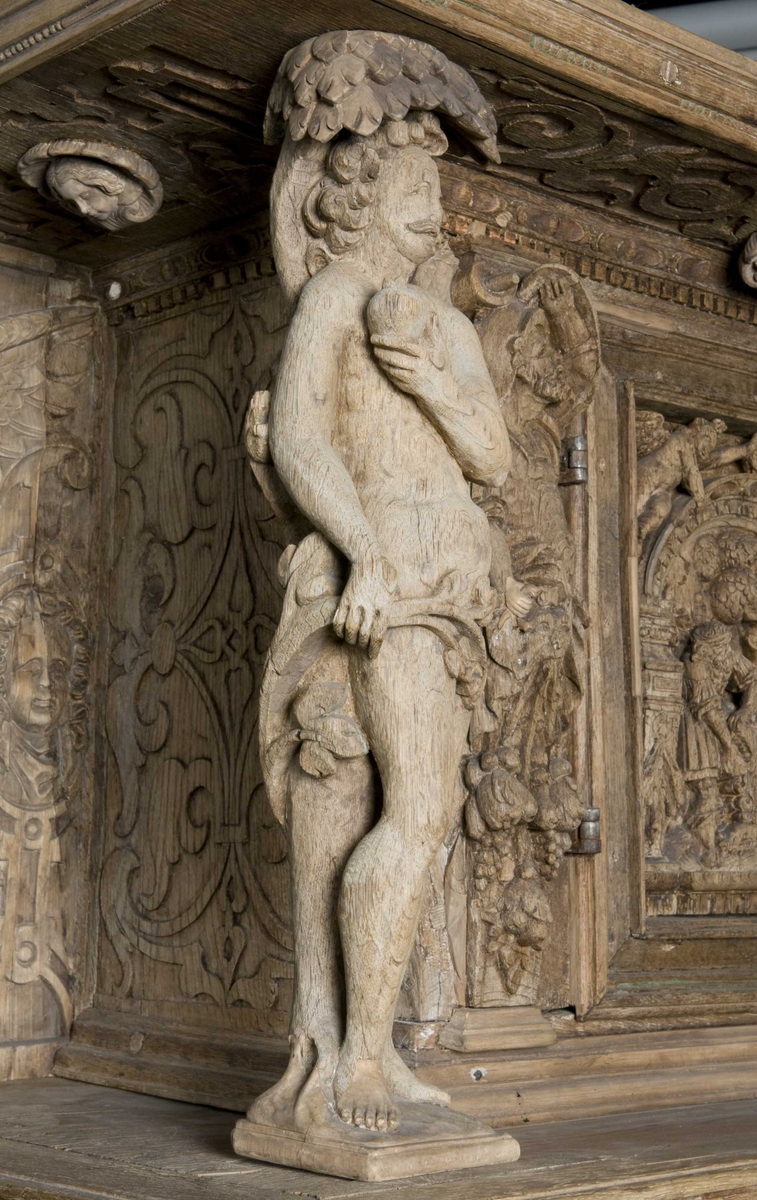 Rektangulært skap med skåret ornamentikk i flere deler. Øvre skap med to dører og gesims. Nedre skap med en klaff fremstilt som to dører. Skapdelene står på en sokkel med fire ben. Tympanon på øvre skap. Skapet ble opprinnelig brukt som skjenk med åpen klaff for å servere drikkevarer til gjester.
På overskapet i dørfyllinger er utskåret motiv fra gamle testament: "Samsons kamp med løven" og "Samson bærer bort Gazas byport". På underskap i fyllinger: "Samson slår filisterne med asenkjeven" og "Samson og Dalila". Dørene blir flankert av hermenpilaster. Mellom fyllinger på overskap aedikula med dyden "kjærlighet".  Som karyatide og atlant to utskårete figuerer "Adam og Eva" ved overskap. 
Klassiske profiler med eggstav, perlestav og tannsnitt. Beslagverkornament på skapsidene, gesimsens underside og profil på underskap. 
Utskårete hoder av løver, engler, kvinner, masker på gesimsens underside og profil på underskap. Sidebrett med hermer, portretter i medaljonger og beslagverk. Sokkelen består av dreide og utskårete ben, holdt av en ramme, Forsidens blending er dekorert med utskårete figurer og ornamenter i ørebruskstil.
Flere deler er sekundære.