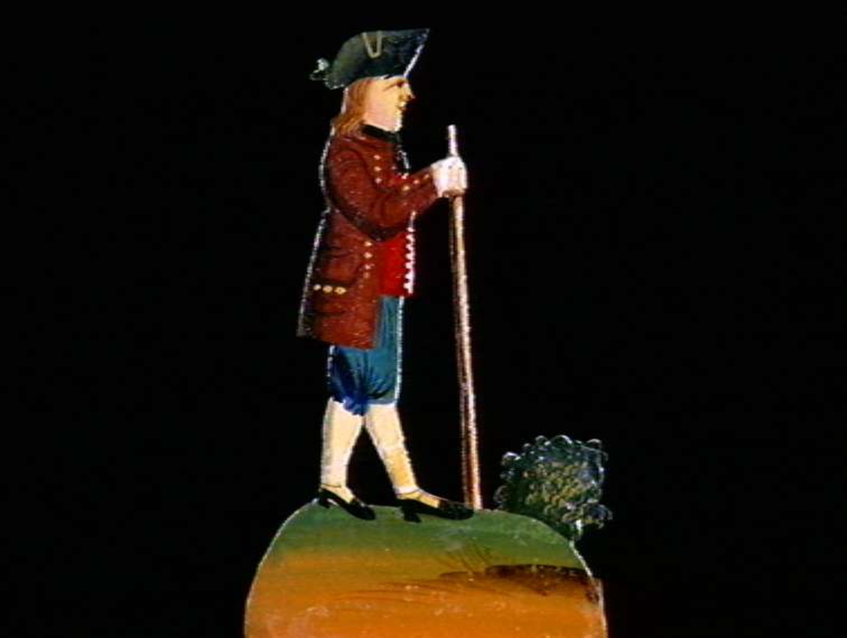 Figurer i papir med trefot i form av husfasader, tær, dyr og mennesker. Tilhørende eske.