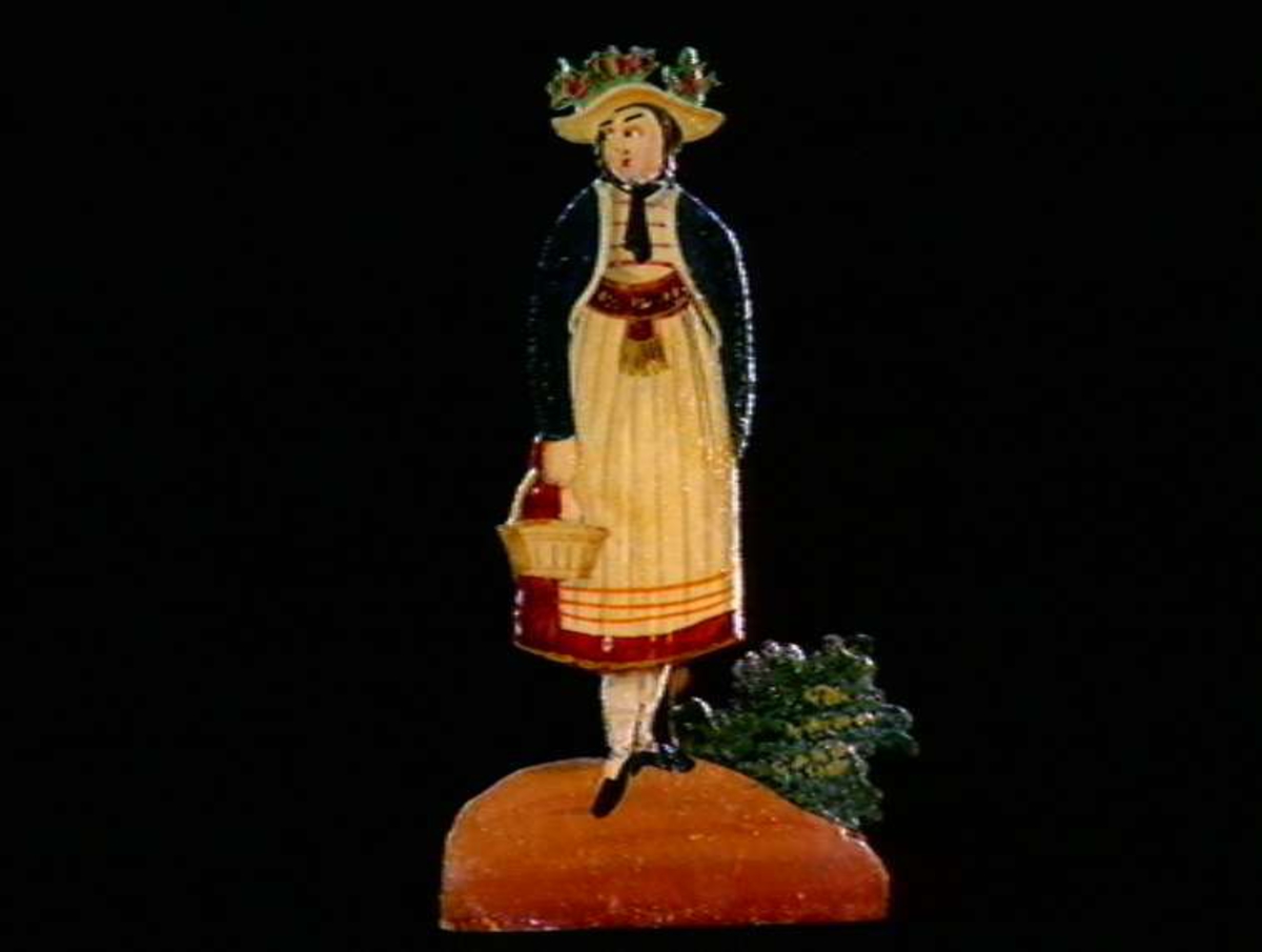 Figurer i papir med trefot i form av husfasader, tær, dyr og mennesker. Tilhørende eske.