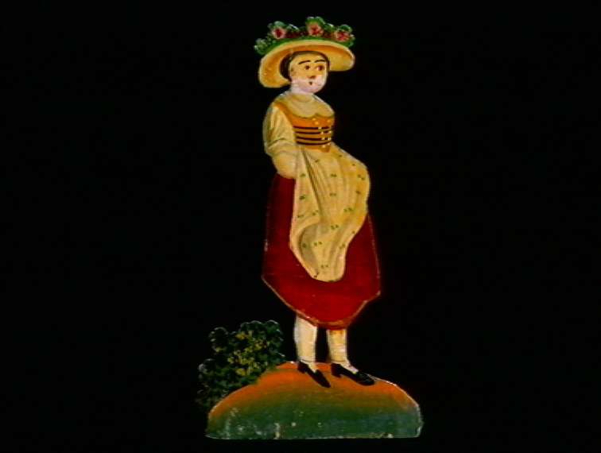 Figurer i papir med trefot i form av husfasader, tær, dyr og mennesker. Tilhørende eske.