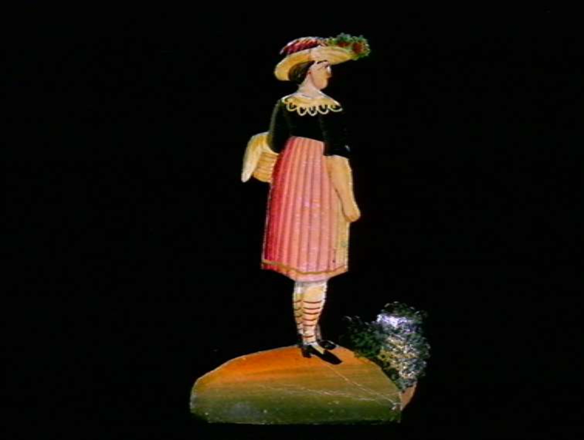 Figurer i papir med trefot i form av husfasader, tær, dyr og mennesker. Tilhørende eske.