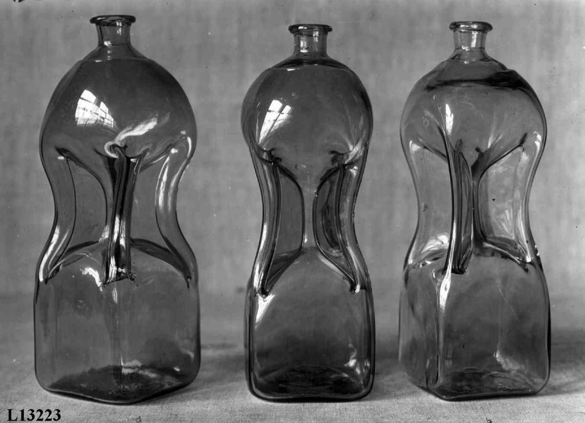 Trekasse med 6 glassflasker og rom i midten for glass. Gamle kalenderblader fra 1824 klistret inni. I lokket klistret en tegning av to damer, vannfarge, signert Hans Johan Fredrich Berg. Lokket foret med grått papir, delvis med rødt trykt mønster.