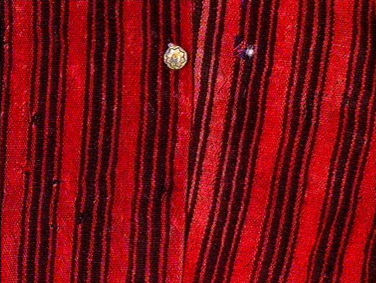 Rød- og svartstripet busserull av heimvevet ullstoff.