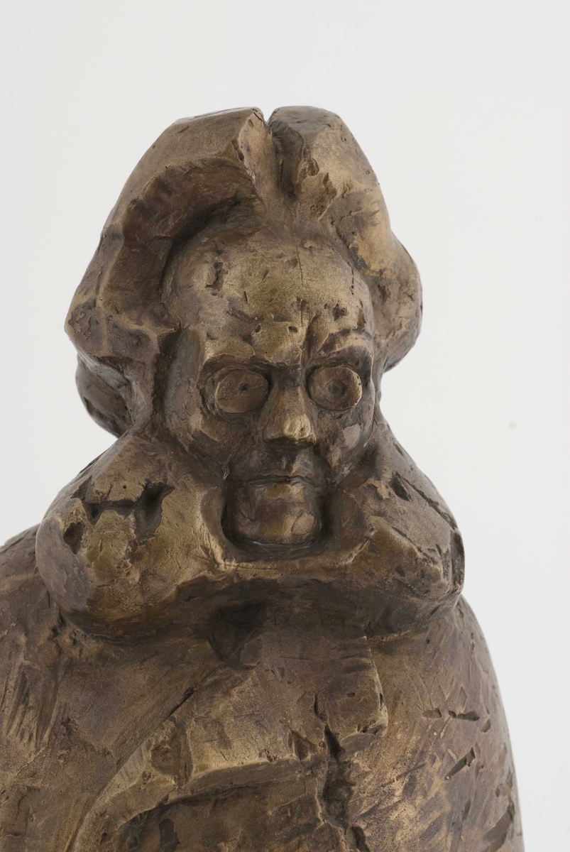 Metallskulptur på tresokkel, plakett på sokkel.