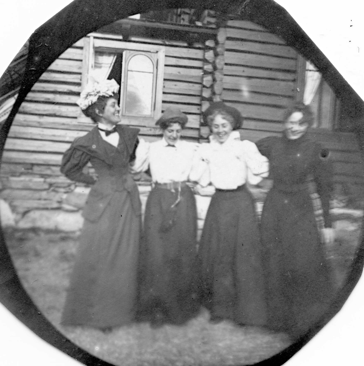 Golå, Sør-Fron, Oppland. Fire kvinner arm i arm foran tømmerhus, Golaa Sanatorium.