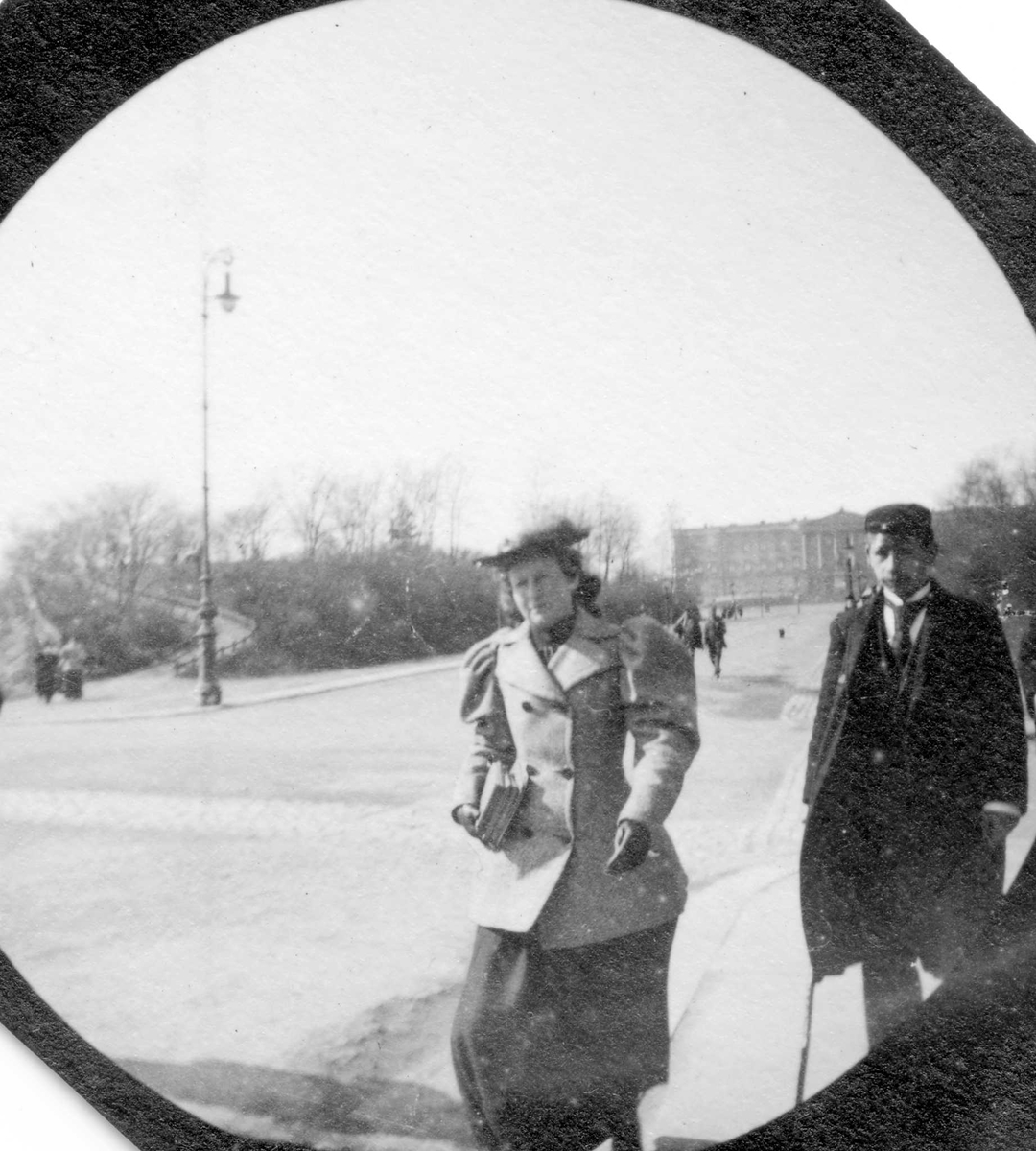 Frk. Sommerville og student Bonnevie spaserer langs Karl Johans gate, Oslo, med Slottet i ryggen.