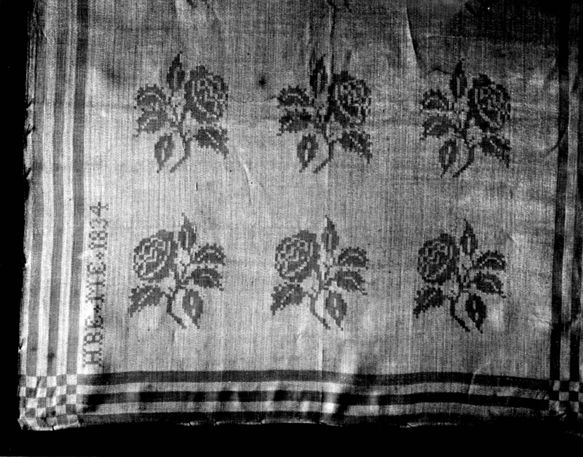 Hvit serviett med mønster av små rosengrener, stripebord. Fra 1834, Larvik, Vestfold. Norsk hjemmevevet damask.