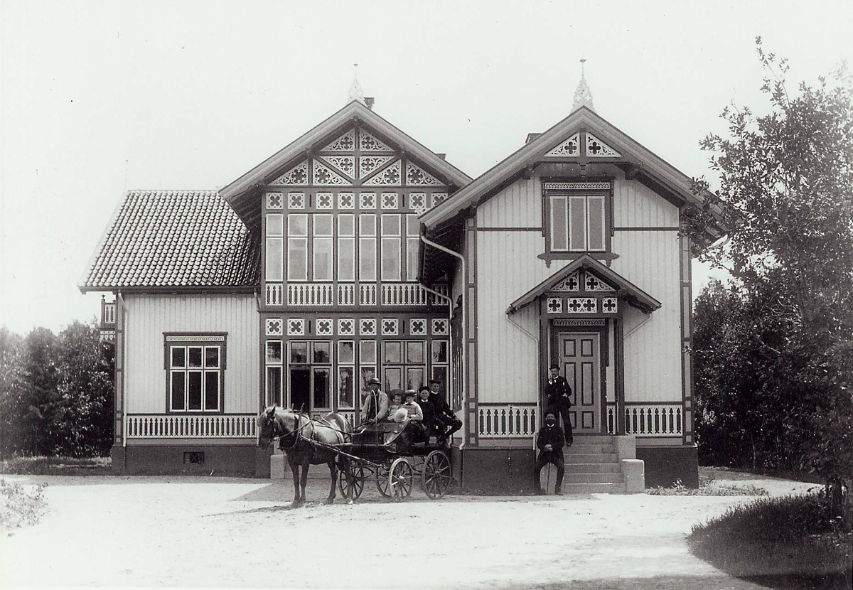Fagerheim, Hisøy, Arendal. Stor sveitservilla tilh. familien Herlofson. Inngangspartiet med persongruppe på trapp og i hestekjøretøy.
Fra serie (NF.04551-001 til -021) fra billedmappen "Strømsbo", gård på Strømsbu i Arendal tilh. familien Herlofson. Bildene er fra ulike eiendommer og steder i Arendal tilknyttet familien, fotografert av P.A. Thorèn, Chra.
