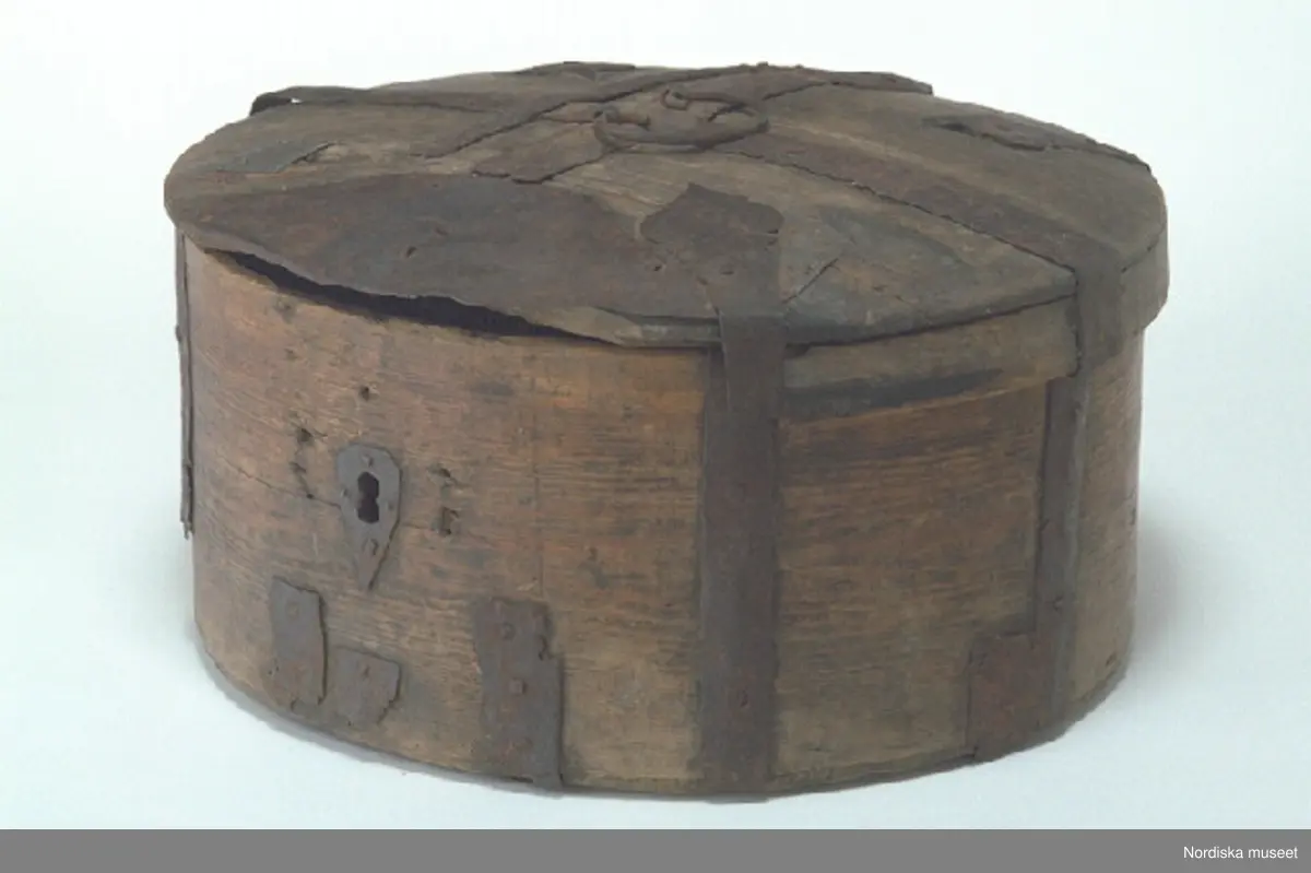 Inventering Sesam 1997-1998:
Diameter 52 (ca), H 28 cm
Resask, runt svepskrin, med svagt kupigt fällock, av barrträ. Botten och lock falsade, fästade vid svepen med järnband, på locket även spetsformiga beslag. Hopfästning av svepen med spikar av järn.
Ett bandgångjärn fästat utvändigt på locket samt runt bottenkanten.
Lås har funnits men fattas nu, nyckelskylt av järn. Bygelhandtag av järn på locket.
Ristade linjer i rutmönster på bottensvepets insida. På locket inristat " A?S " samt " LBS ".
Botten och lock har flera sprickor. Locksvepet är trasigt med en stor del borta. Järnbeslagen mycket rostiga, flera bitar har fallit bort, lagat med järn- och zinkplåt.
Agnetha Blomberg 1998