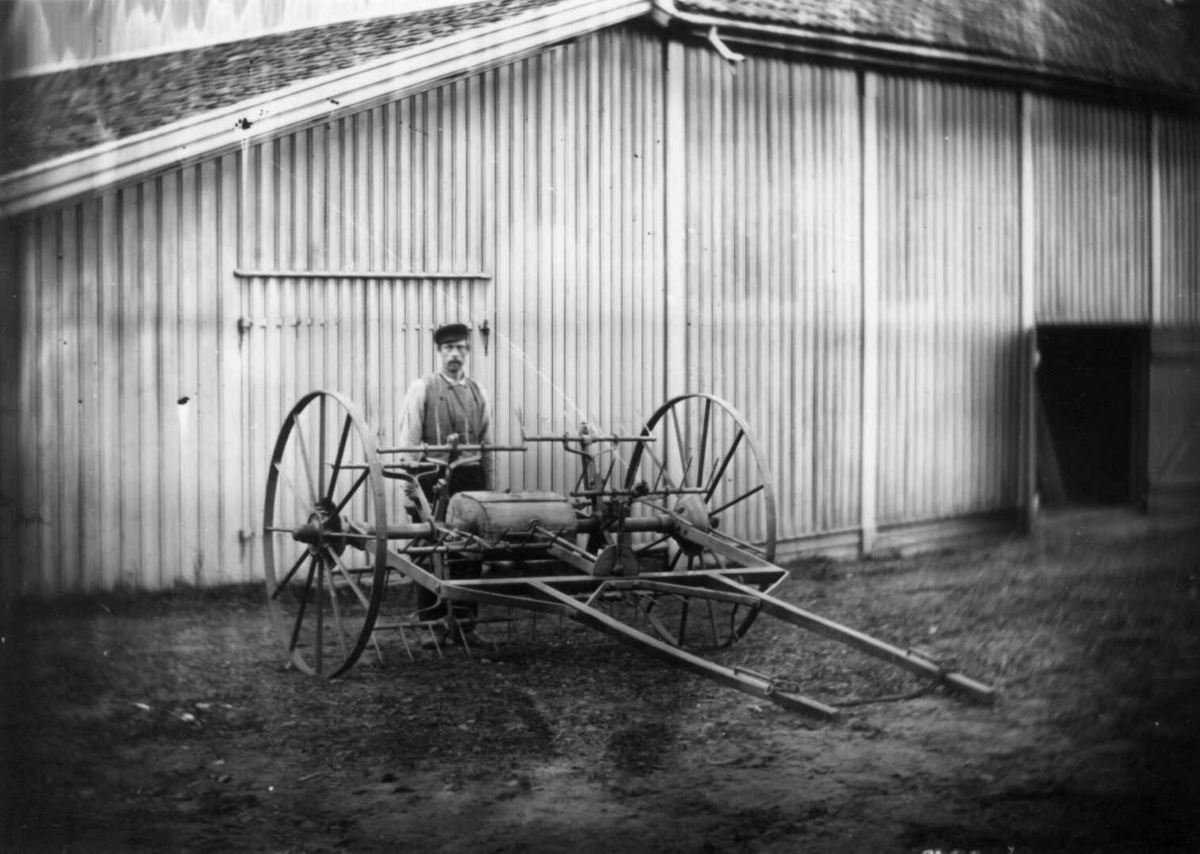 Hjulrive, Dal gård, Ullensaker. Gårdsarbeider bak hjulrive foran uthus.
Fra serie fotografert av kammerherre Fredrik Emil Faye (1844-1903), gårdens eier.