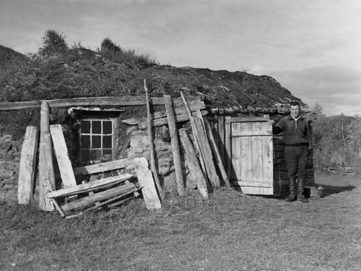 Boliggamme med smårutet vindu, innvendig panelt. En mann (Per Setereng, 1905-1998) står i døråpningen. Valjok 1940.