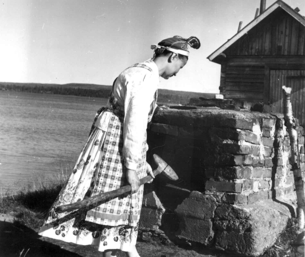 En kvinne foran bakerovn utenfor en bygning. Kirakka järvi 1959.