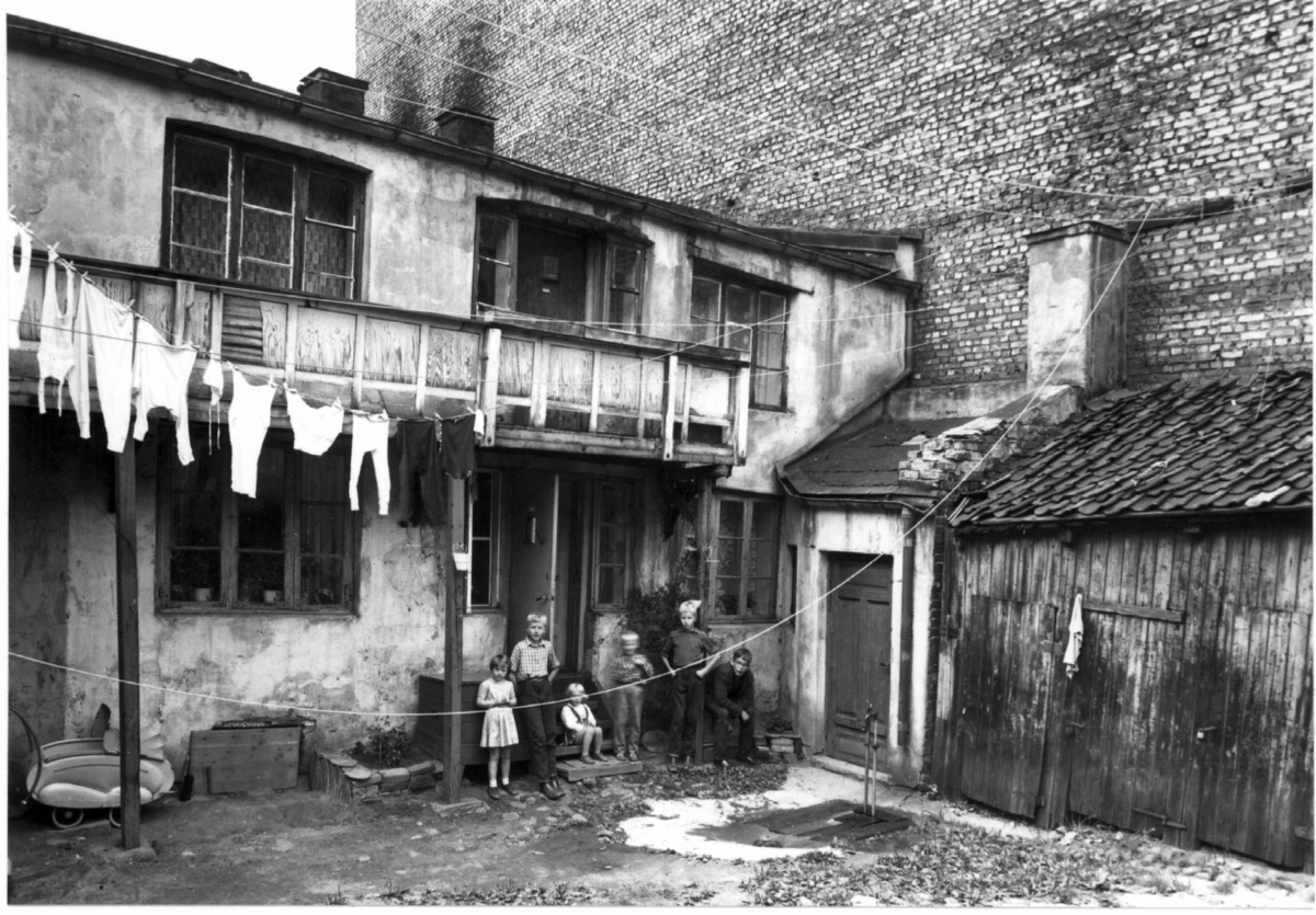 Stolmakergata 12, Oslo 1961. Bakgårdsbygninger, bolig og.uthus. Barn oppstilt foran inngangsdør.